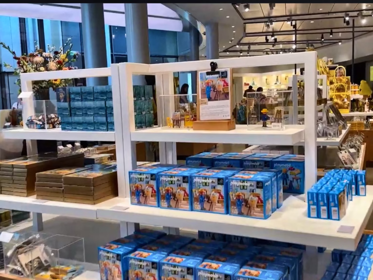 The interior of the Van Gogh Museum shop features various merchandise displayed on white shelves for visitors to browse