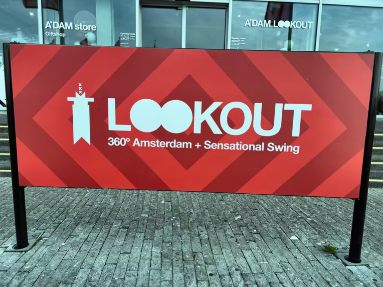 A large sign at a'dam lookout features bold lettering promoting a 360° view of amsterdam and a swing attract in A’DAM Lookout