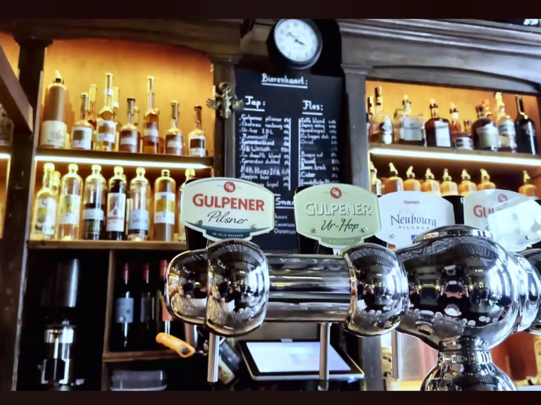 The scene shows a bar with beer taps and shelves filled with bottles in the Brown cafe ambiance