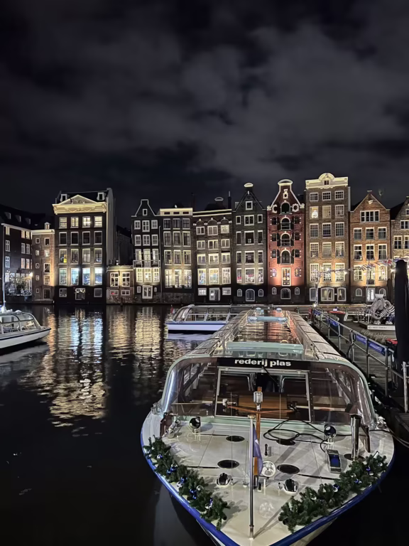 Illuminated canal houses reflect off the water near a moored boat creating a serene atmosphere for a Canal Cruise