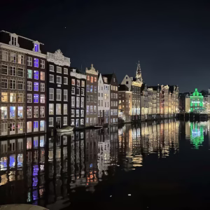 A night view of the illuminated Canals Amsterdam with colorful reflections on the water showcasing historic buildings along t