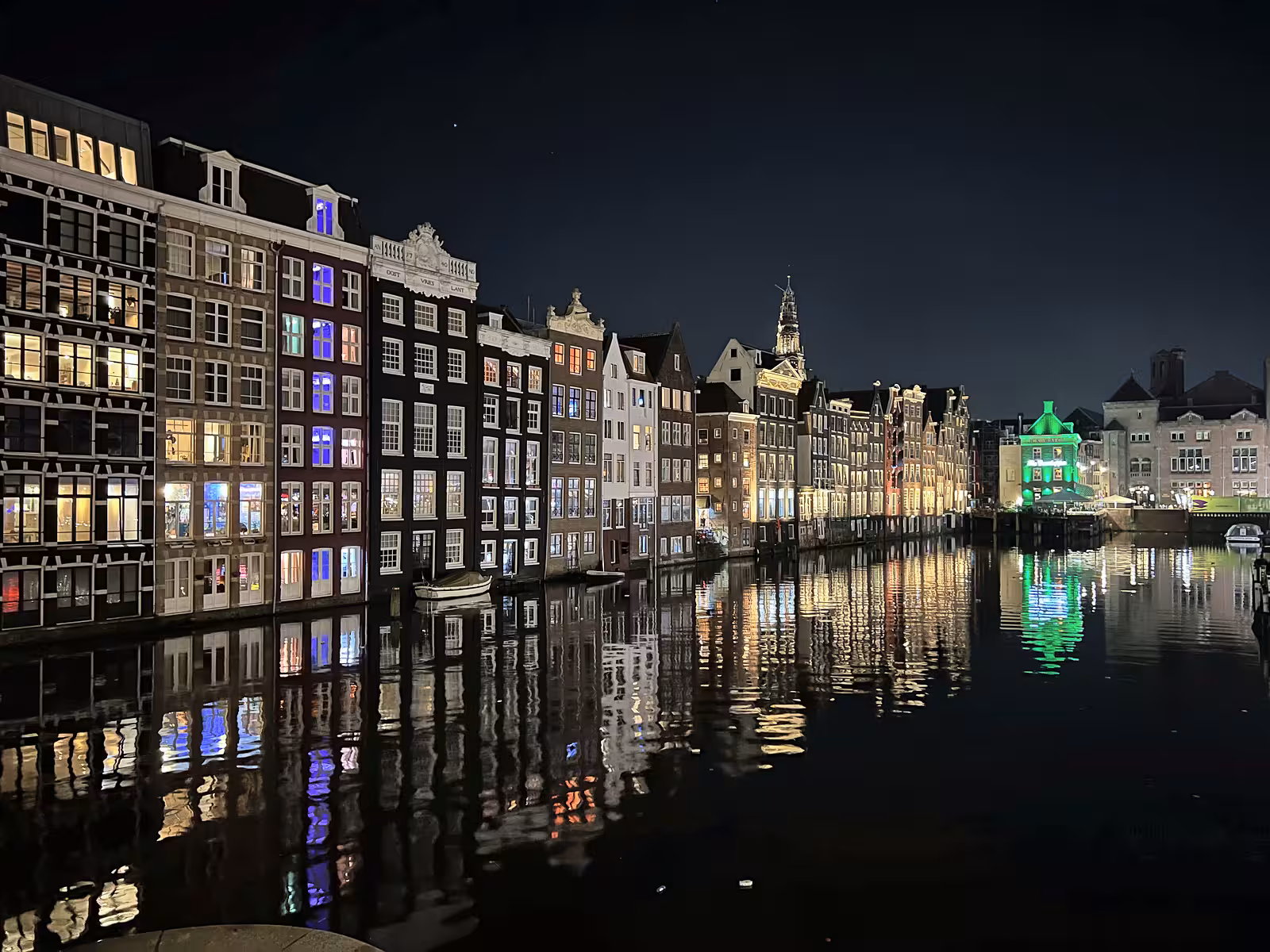 A night view of the illuminated Canals Amsterdam with colorful reflections on the water showcasing historic buildings along t