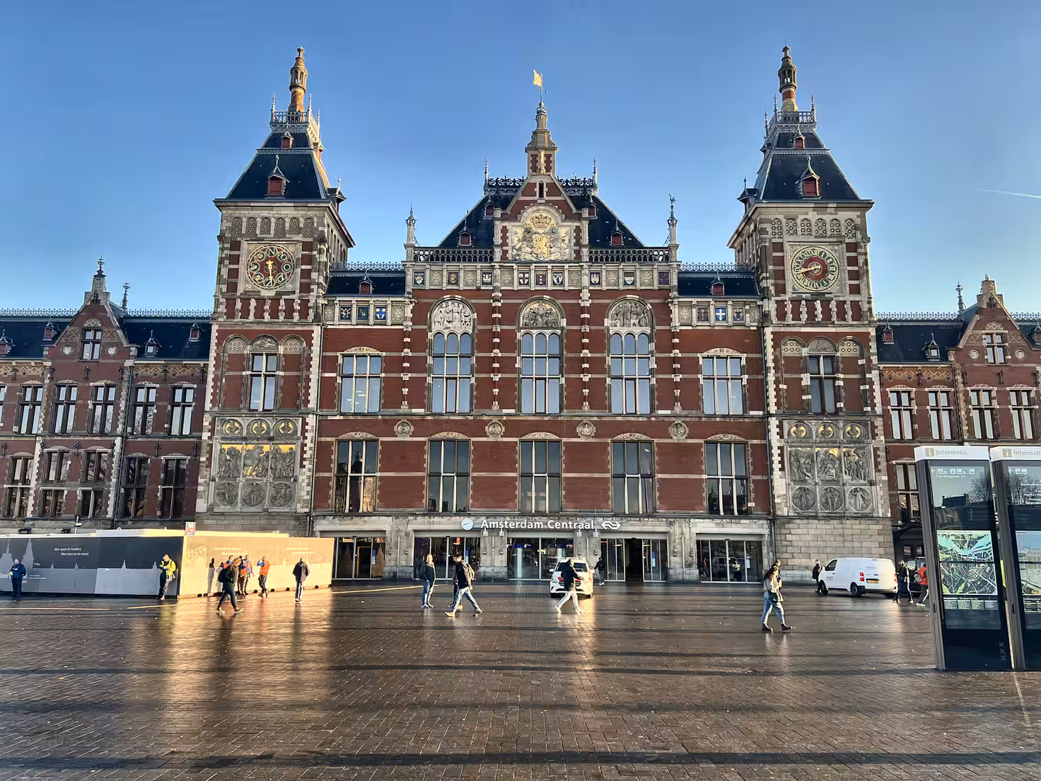 Centraal Station features stunning architecture with red bricks intricate detailing and pedestrians strolling in bright dayli