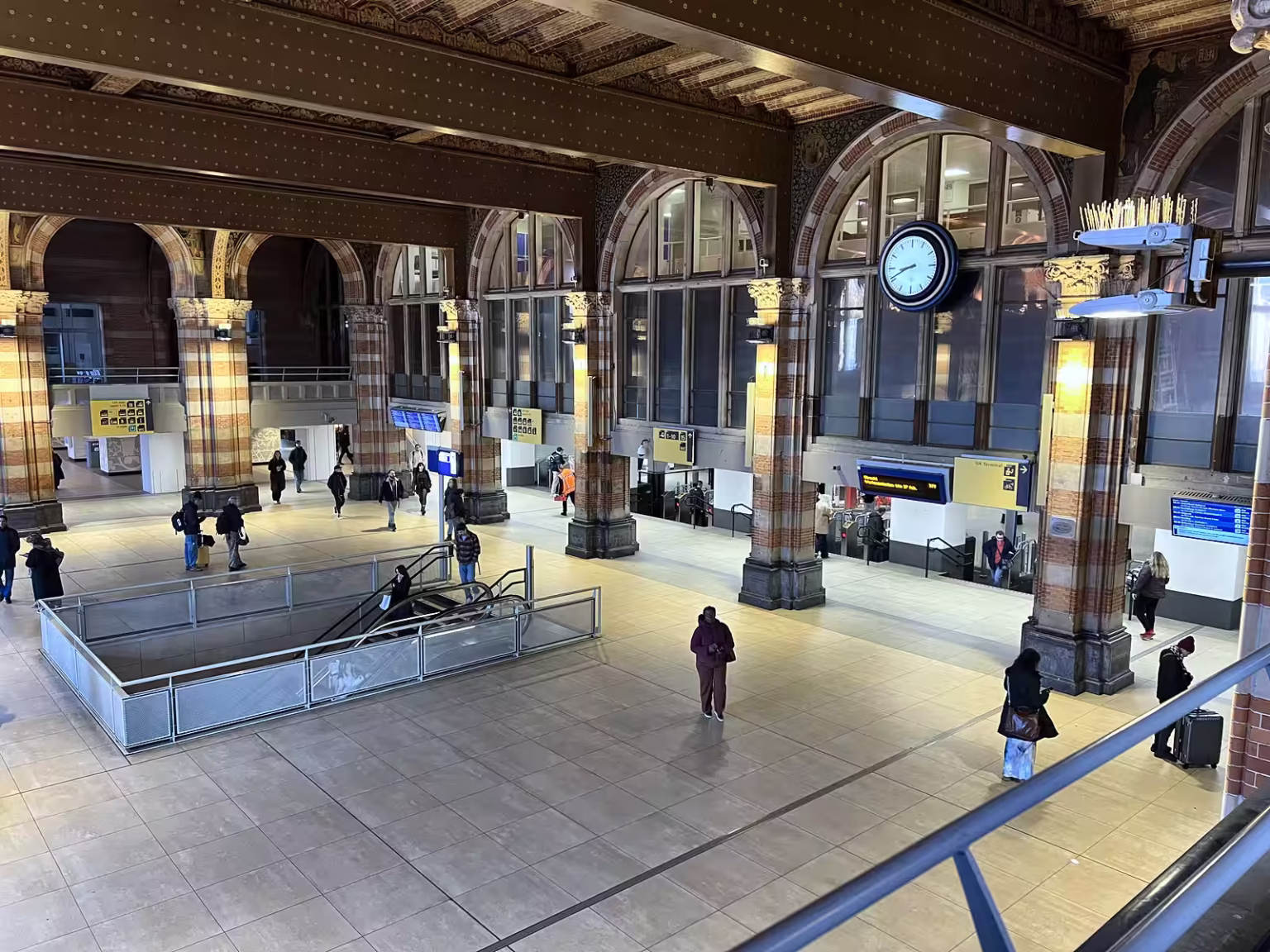 The interior of Centraal Station shows a spacious area with high ceilings elegant arches and a large clock bustling with trav