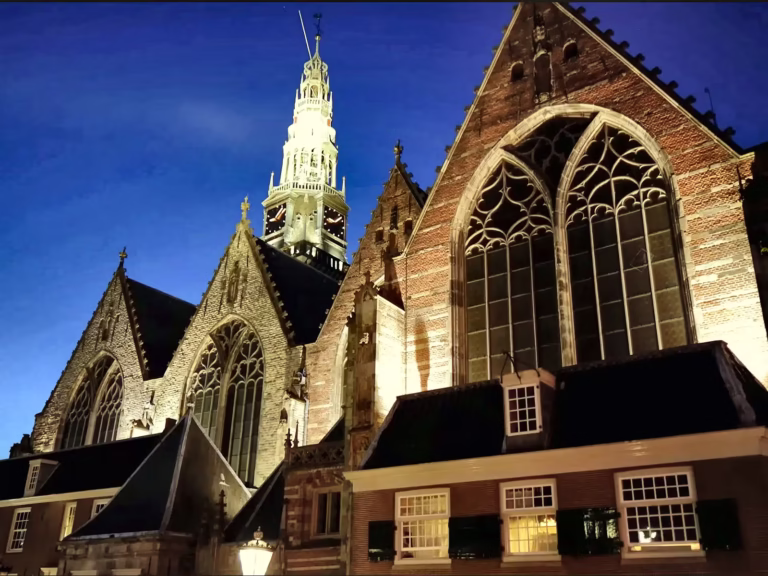The illuminated church tower shines brightly against the night sky showcasing its gothic architecture near De wallen