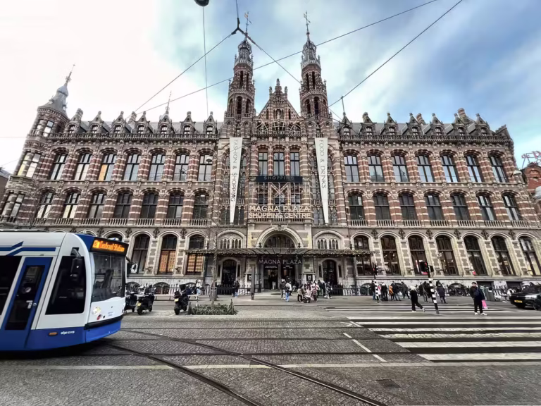 The impressive facade of Magna Plaza showcases intricate architectural details and bustling street activity