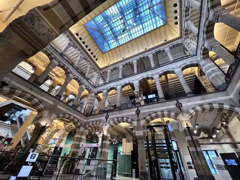 The interior of Magna Plaza features grand arches and a glass ceiling allowing natural light to illuminate the space