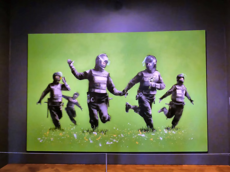 The mural at the Moco museum features several figures in riot gear playfully interacting in a bright green field