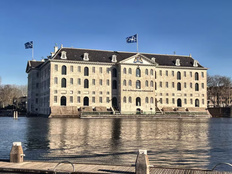 The National Maritime Museum stands prominently by the water showcasing its historical architecture and the flags fluttering - Museums & Art