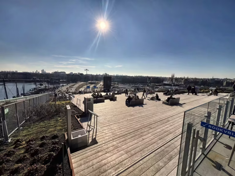 The sun shines brightly over the outdoor area of the NEMO Science Museum where visitors relax and enjoy the view