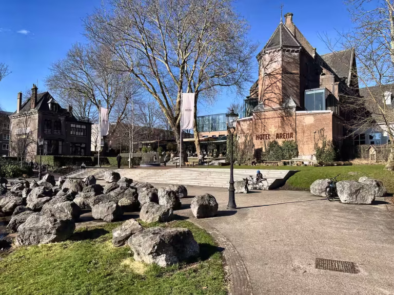 Oosterpark features a scenic view with large rocks greenery and the historic hotel arena in the background