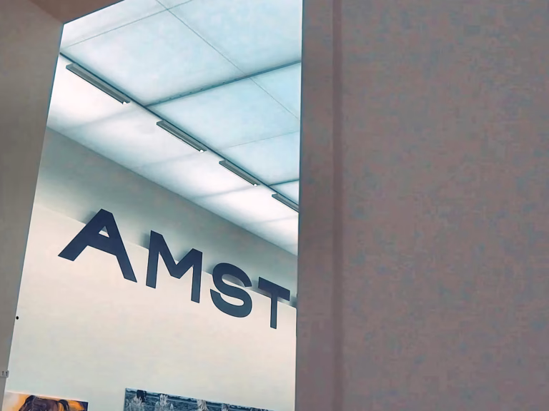 The image shows part of the Stedelijk museum with the word "amst" visible on the wall and ceiling lights above