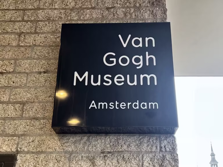 The sign of the Van Gogh Museum is prominently displayed on the wall showcasing its name and location in amsterdam