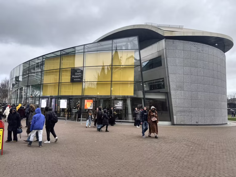 People gather outside the modern entrance of the Van Gogh Museum showcasing its striking architecture and vibrant colors