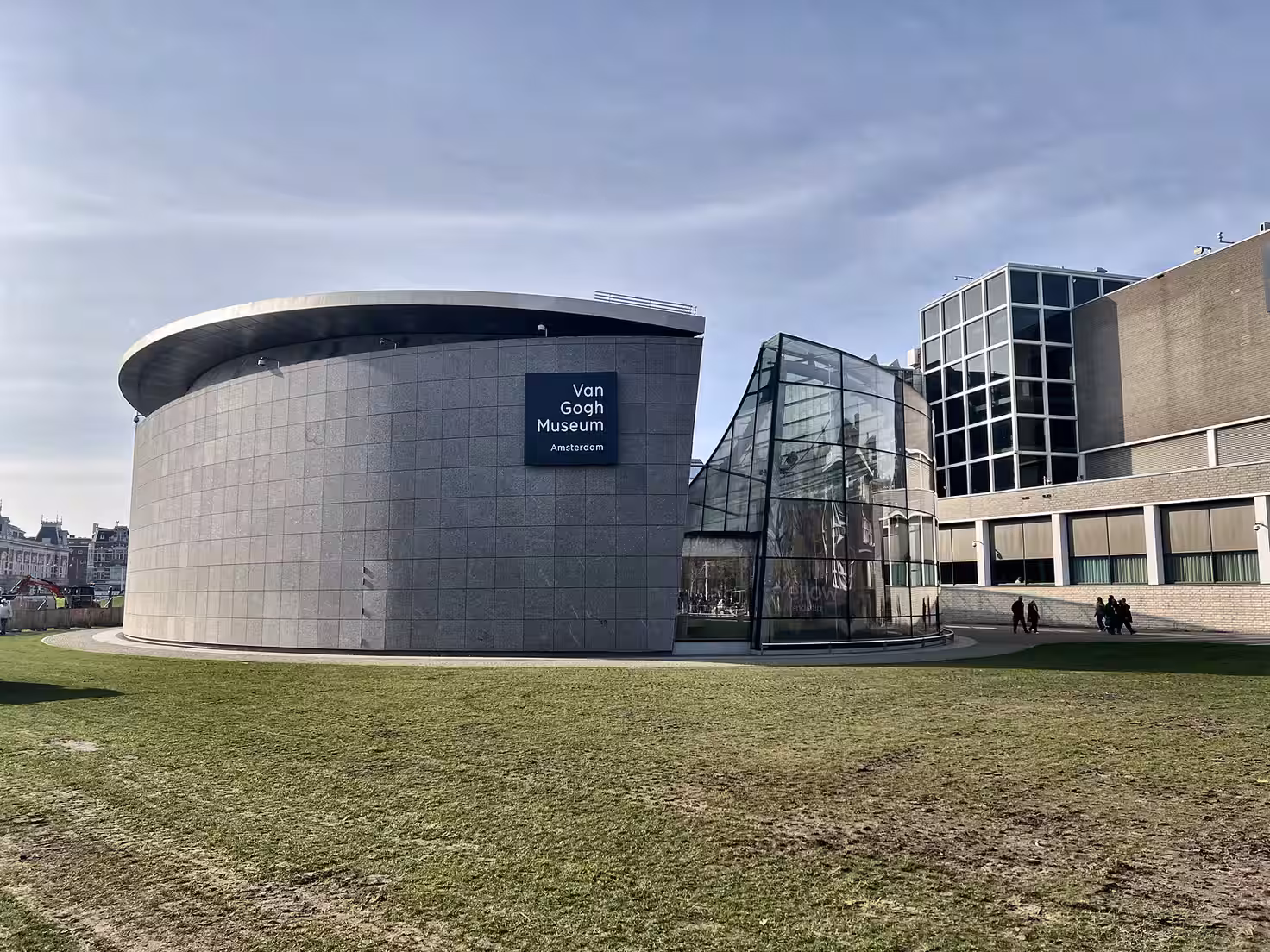 The modern exterior of the Van Gogh Museum featuring a round stone structure and glass components showcasing